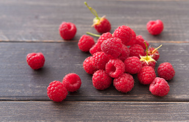 Red fresh raspberries on brown rustic wood background