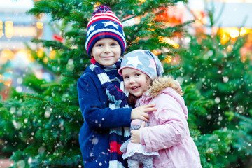 Two little smiling kids, boy and girl with christmas tree