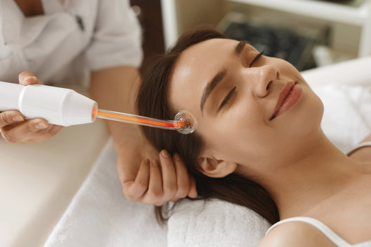Face Beauty Treatment. Woman Using Darsonval Skin Care Device