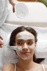 Facial Beauty Treatment. Beautiful Woman Getting Cosmetic Mask