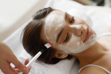 Facial Beauty Treatment. Beautiful Woman Getting Cosmetic Mask