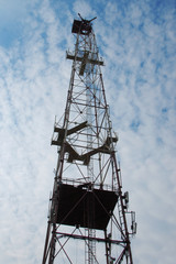 Telecommunications tower with blue cloudly sky transmitting the signal