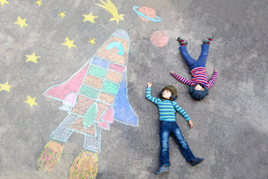 Two little kid boys flying by a space shuttle chalks picture
