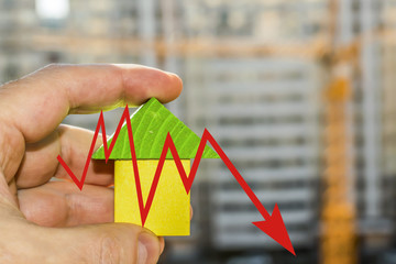 Wood house in hand on a background of construction   The concept of price changes on the real...