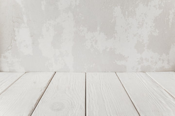 Old plaster wall with white wooden floor, close-up. Abstract empty interior background, free space