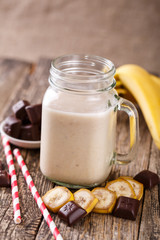 Banana smoothie  with chocolate in glass jar with drinking straw