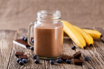 Chocolate smoothie in glass jar with blueberries and drinking st