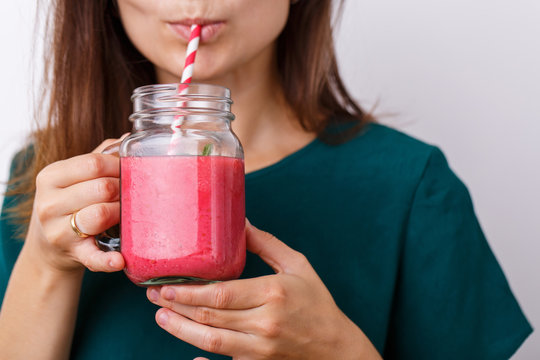 Young woman drinks detox drink, smoothie in glass jar.