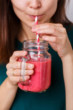 Young woman drinks detox drink, smoothie in glass jar.