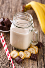Banana smoothie  with chocolate in glass jar with drinking straw