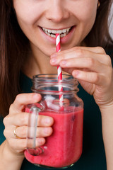 Young woman is holding detox drink, smoothie in glass jar.