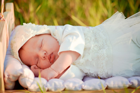 A Tiny Baby Asleep In His Crib In Lace Bonnet