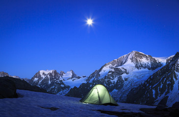 The moon rising above a tent in the mountains in Wallis, Switserland. Outdoor and adventure concept. © sanderstock