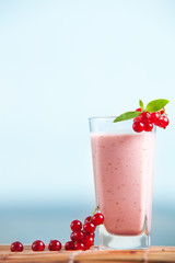 Red currant milkshake with mint leaves and sea on the background. Healthy summer drink with milk and icecream. Cold fresh smoothie.