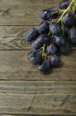 Black grapes on a rustic wooden table top background forming a page border