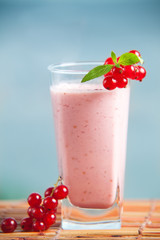 Red currant milkshake with mint leaves and sea on the background. Healthy summer drink with milk and icecream. Cold fresh smoothie.