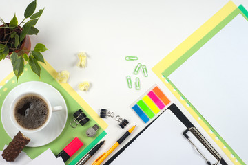 Office table desk with set of colorful supplies, white blank note pad, cup, pen, crumpled paper, flower on white background. Top view and copy space for text