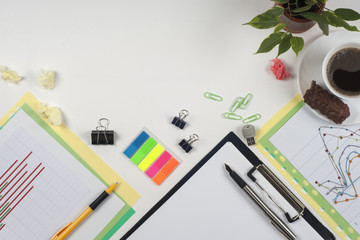 Office table desk with set of colorful supplies, white blank note pad, cup, pen, crumpled paper, flower on white background. Top view and copy space for text