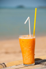 verre de jus d'orange avec une paille sur la plage
