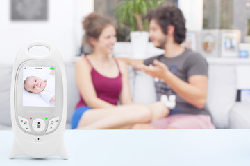 Couple enjoying free time not noticing that their baby isn't sleeping on baby monitor, copy space