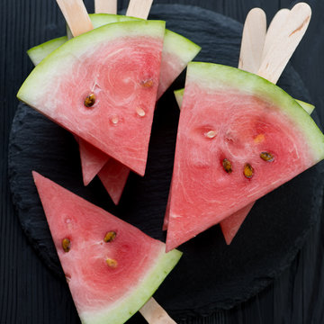 Top view of ripe juicy watermelon slices on sticks, close-up