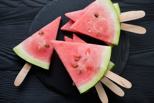 Summer refreshment with juicy watermelon on sticks, top view