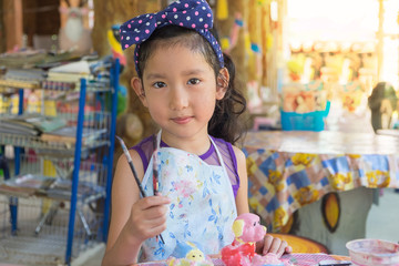 Cute asian girl show her paint brush.