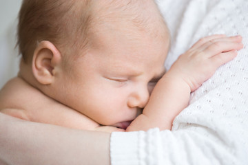 Close-up portrait of funny newborn babe napping in mom arms. Adorable new born child sleeping on mom hands. Healthy little kid asleep. Love, bonding, happy family concept.