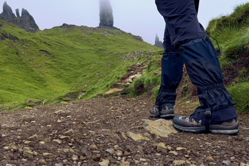 Man wearing trekking boots and gaiters walking to the Old man of Storr, Scotland