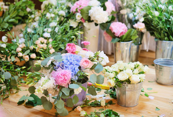 Florist workspace for decorating wedding reception at restaurant with flowers, accessories, vases