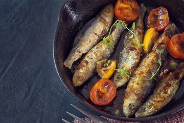 Grilled fish with cherry tomato in cast iron skillet 