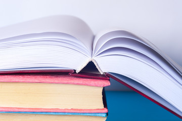 Open book, stack of colorful hardback books on light table. Back to school. Copy space for text