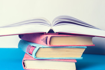 Open book, stack of colorful hardback books on light table. Back to school. Copy space for text