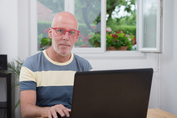 mature man with laptop in his home