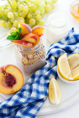 Healthy breakfast: muesli with smoothie, honey, yogurt and fresh berries in a glass jar on white wooden background