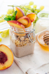 Healthy breakfast: muesli with smoothie, honey, yogurt and fresh berries in a glass jar on white wooden background