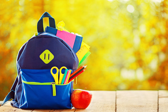 Full School backpack on wooden and autumn nature background