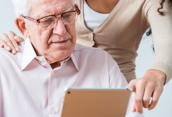 Woman helping elderly man to read questionnaire