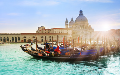 Fototapeta na wymiar Beautiful view of traditional Gondola on famous Canal Grande with Basilica di Santa Maria della Salute in golden evening light at sunset in Venice, Italy