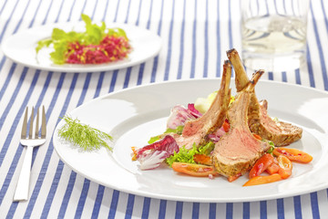 Roasted lamb rib chops with vegetables, dinner setting.