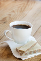 White cup of black coffee with chocolate wafers