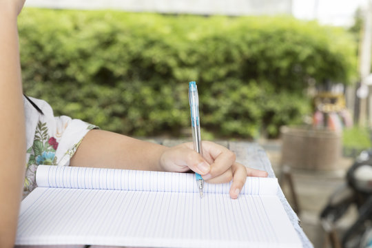 girl holding pen writing on notebook