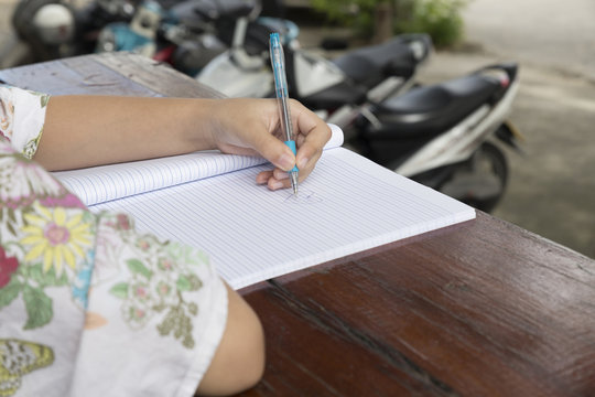 girl holding pen writing on notebook