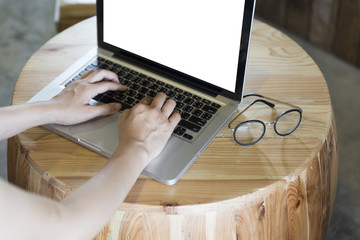 woman's hand on computer notebook with eyeglasses on wooden desk