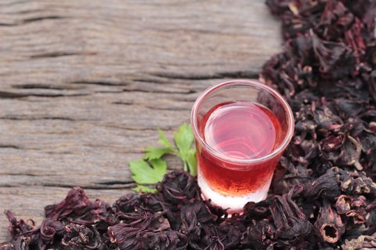 Dry roselle and roselle juice on wood background.