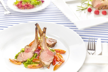 Roasted lamb rib chops with vegetables, dinner setting.