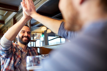 happy male friends making high five at bar or pub