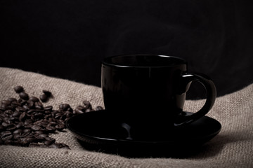 Coffee beans and coffee in cup on burlap. Selective focus. Toned