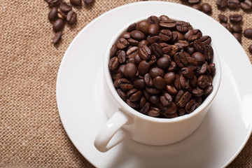 Coffee beans and coffee in cup on burlap. Selective focus