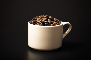 Coffee beans in the cup on black background. Toned